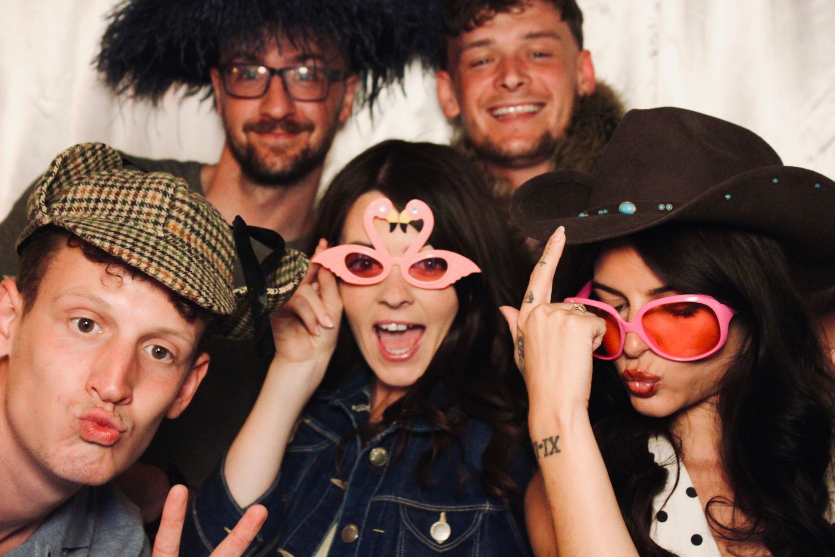 Guests posing with feathered hats, cowboy hat and novelty glasses in the VW PhotoBus booth